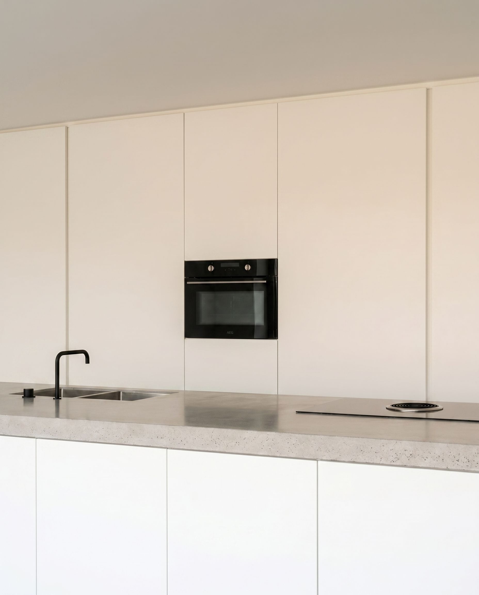 Raumperspektive einer minimalistischen Inselküche in Backnang mit fugenlosem Estrichboden.